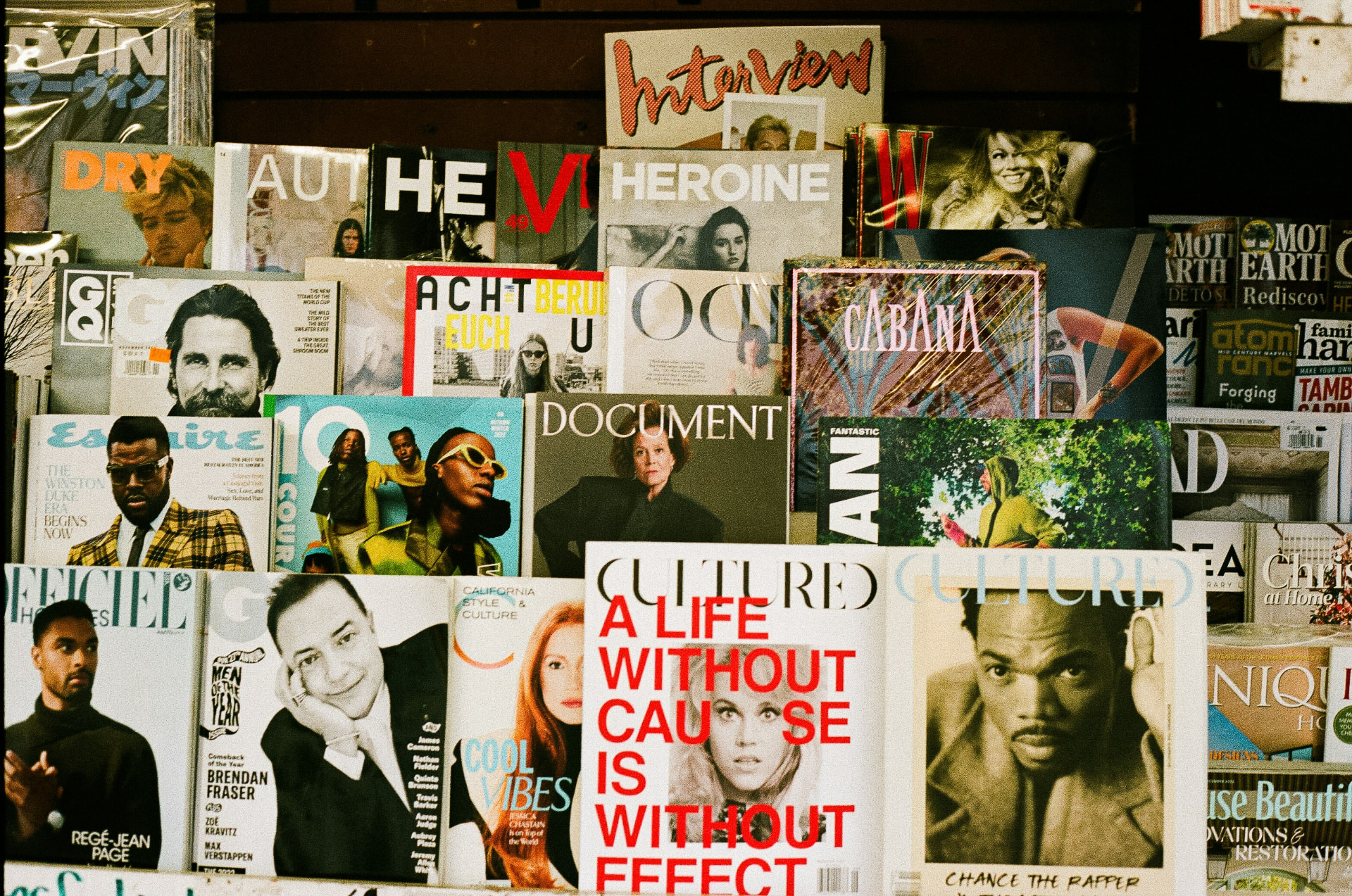 A dense newsstand wall lined with Vogue, Elle, Bazaar, GQ and other international magazine covers.