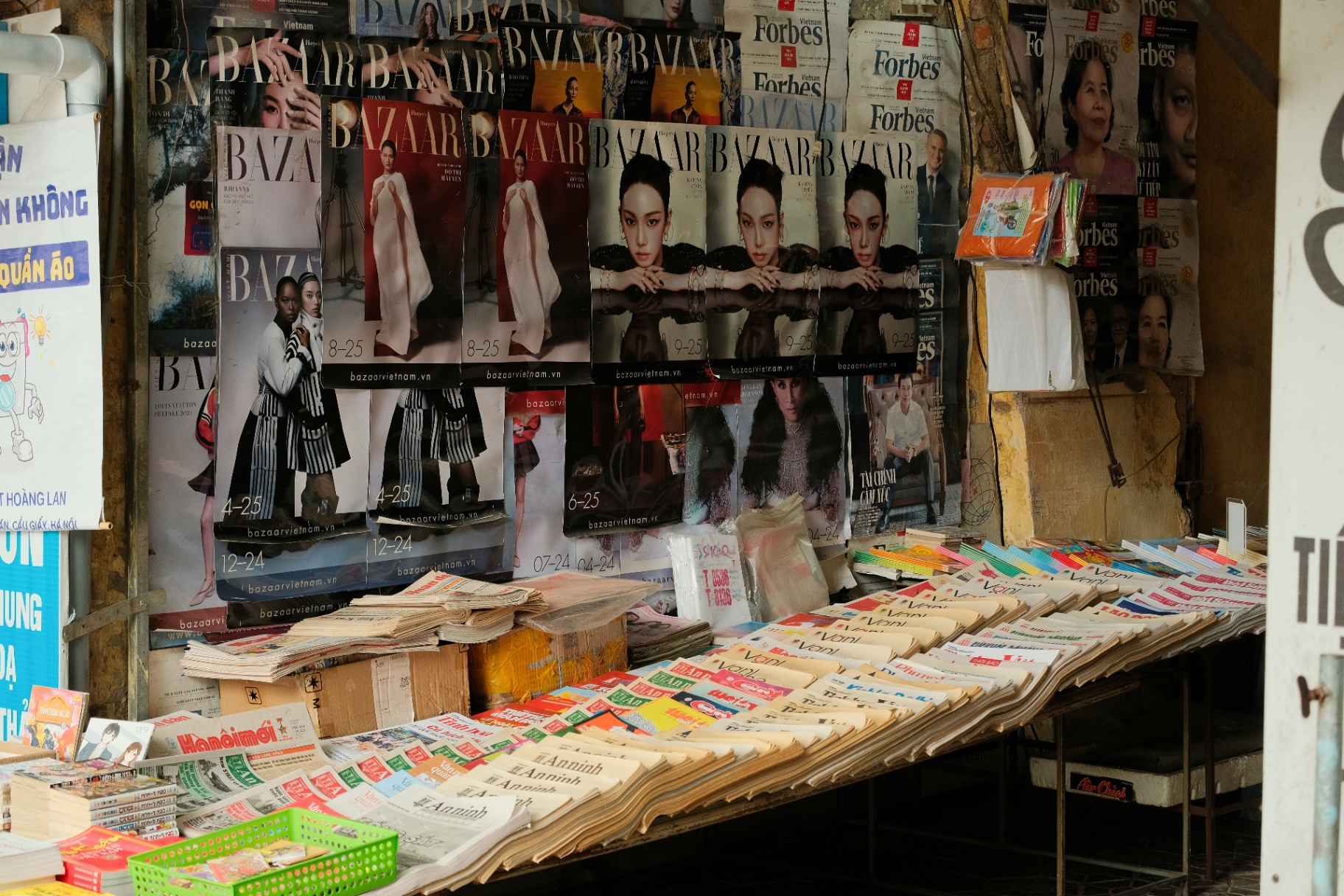 A dense newsstand wall lined with Vogue, Elle, Bazaar, GQ and other international magazine covers.