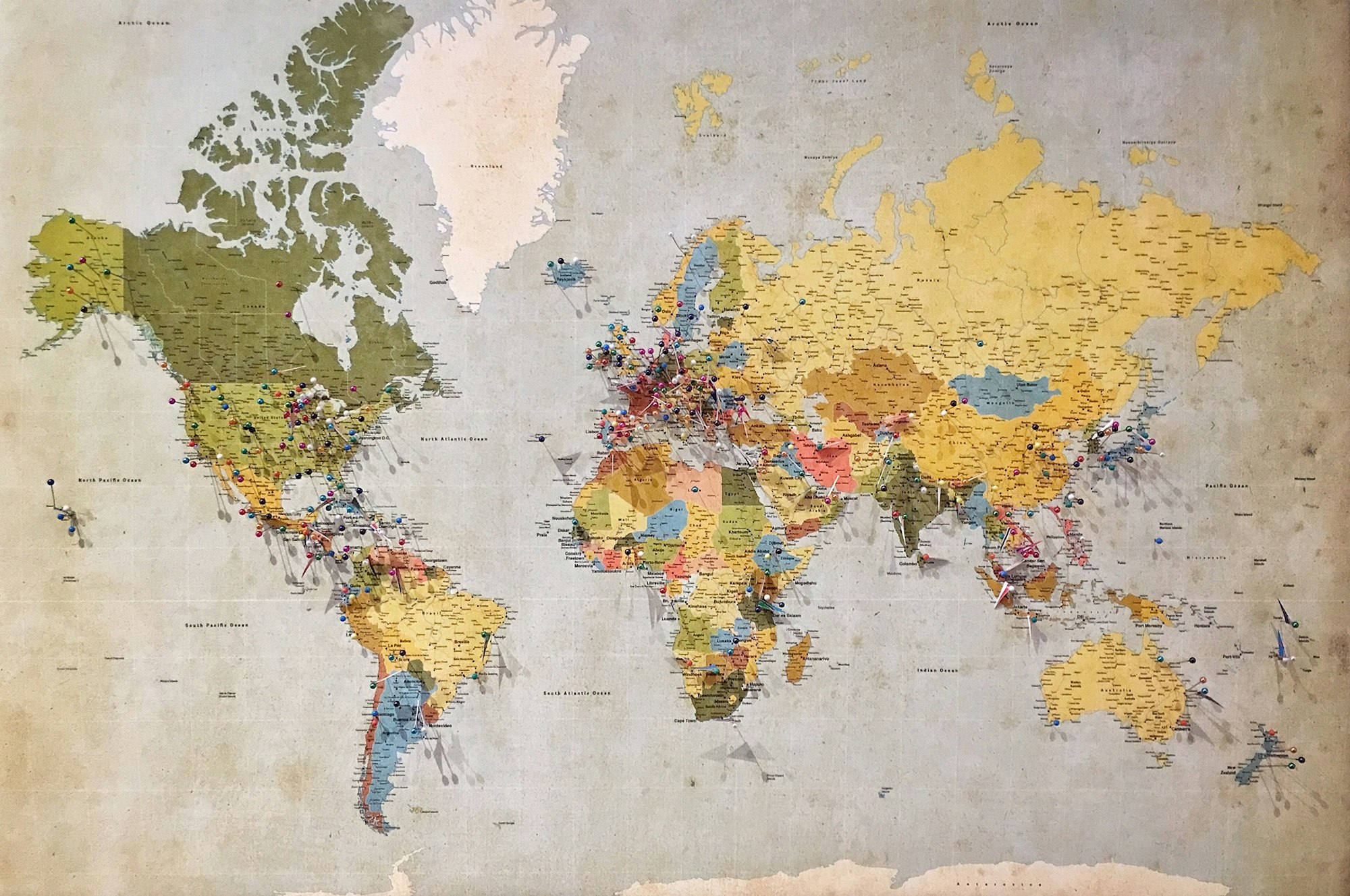 A vintage paper world map covered in travel pins.